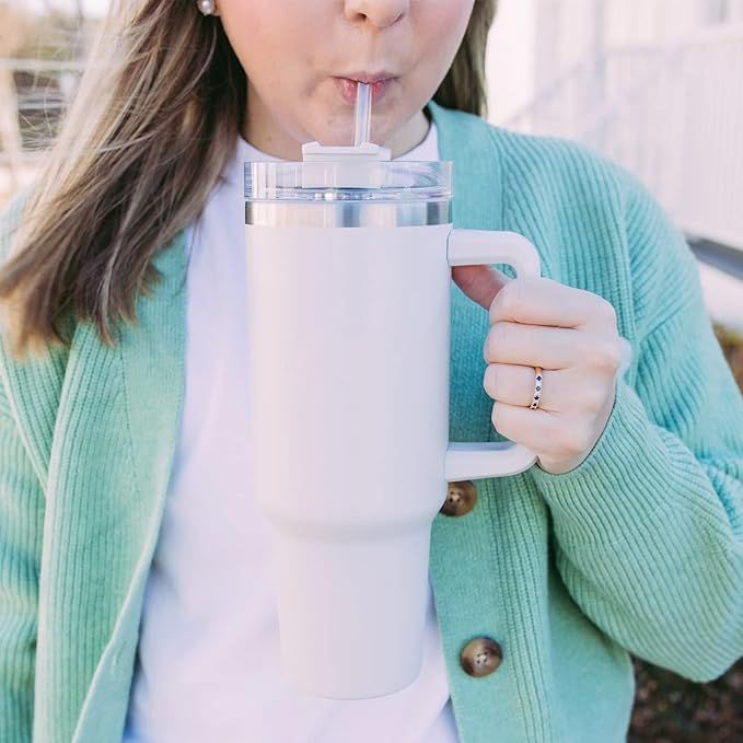 Person in a green cardigan drinking from a white 40oz tumbler with a handle and straw
