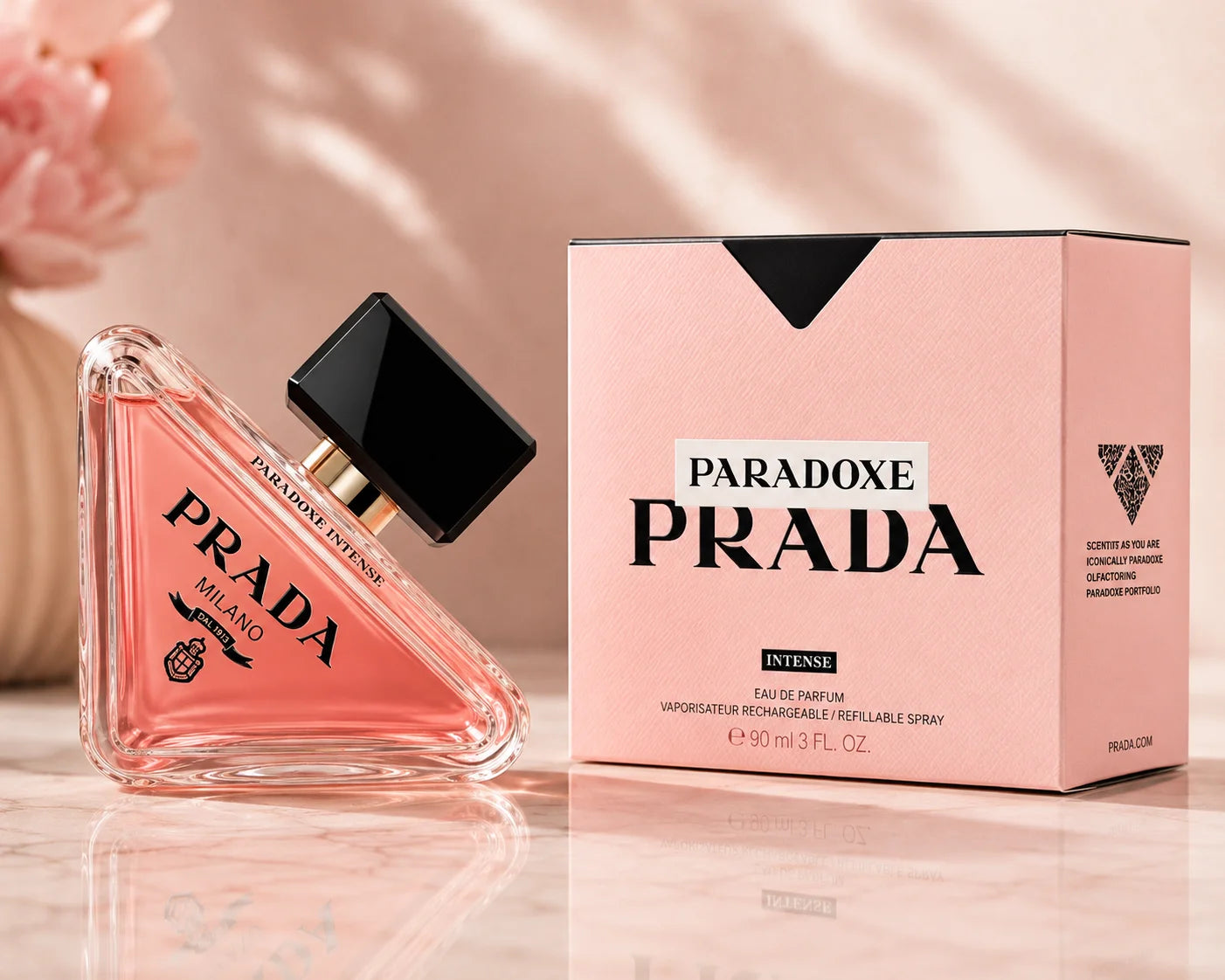 Prada Paradoxe Intense Eau de Parfum bottle next to its pink packaging box on a light marble surface with soft shadows.