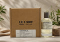Le Labo Coriandre 39 perfume bottle next to its brown cardboard packaging box, styled on a stone surface with a linen cloth and green leaves in the background.