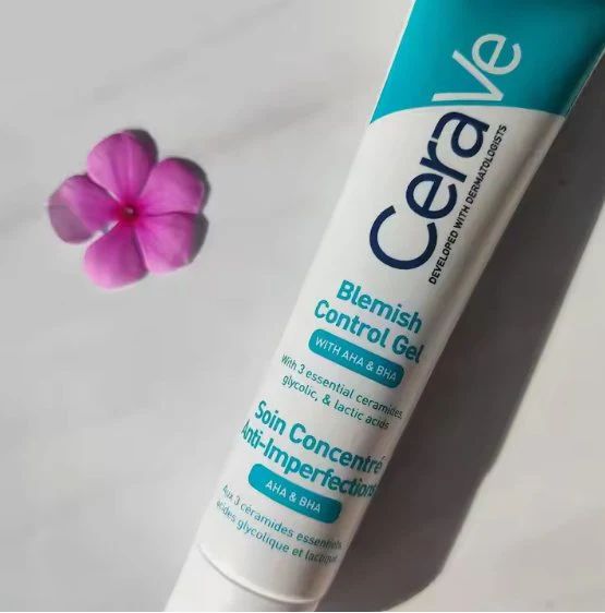 Close-up of the CeraVe Blemish Control Gel tube next to a pink flower on a white background.