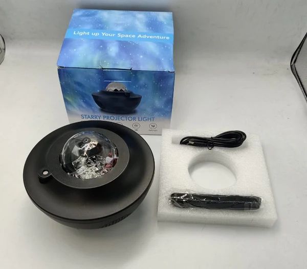 Starry projector light with packaging, cable, and remote control on a white surface