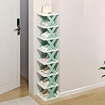 White and mint-green X-shaped shoe rack in a hallway corner, holding shoes and a bag on top, next to a door.